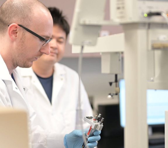 Two people in lab coats working together in a lab.