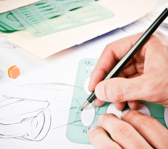 A person drawing a car using a round-shaped ruler.