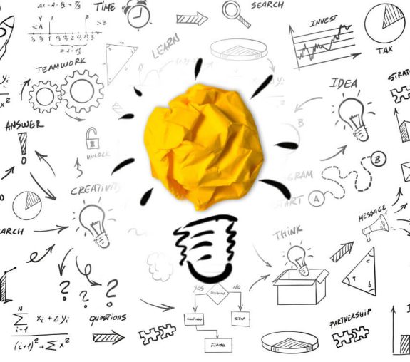A light bulb with yellow crumpled paper surrounded by scribbles, symbolizing an idea or the brainstorming process.