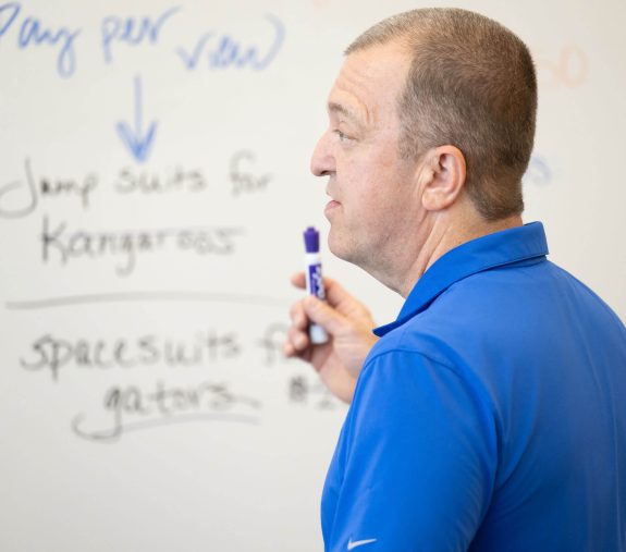 UF staff explaining something he wrote on the whiteboard.