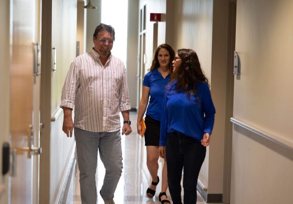 UF Innovate team members speaking with a client and walking together in a hallway.