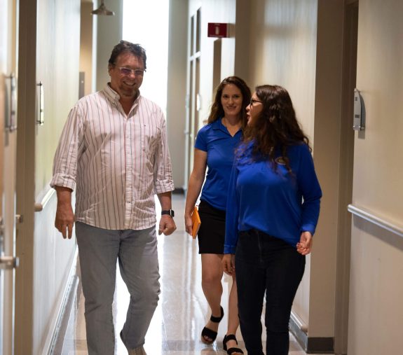 UF Innovate team members speaking with a client and walking together in a hallway.