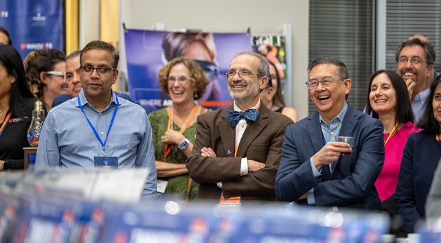People smiling together as they look at something during the Standing InnOvation.